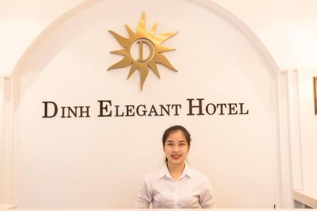 A reception desk at Dinh Elegant Hotel with a sun emblem and a sign above.