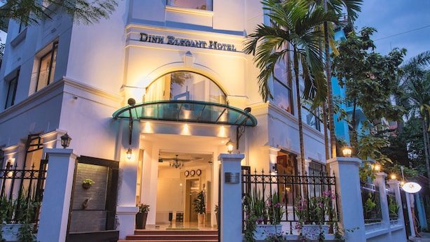 La entrada del Hotel Dinh Elegant, con una cubierta de vidrio, una escalera doble y un acceso portón.