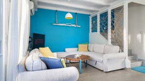 A modern living room with a blue accent wall, white sofas, and a wooden coffee table. - Seabreeze Villa - with Jacuzzi & heated pool (Kos)