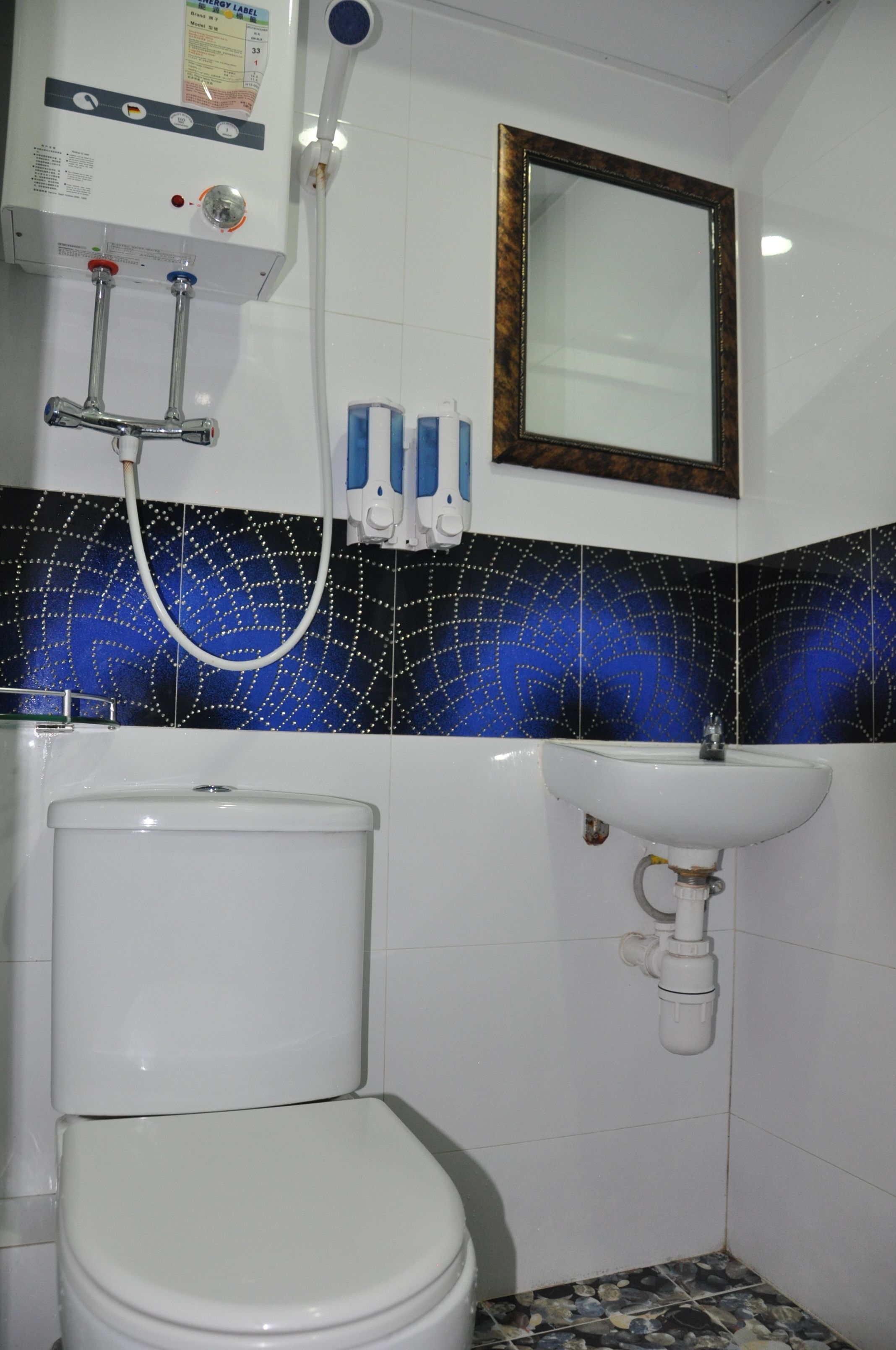 A bathroom with a toilet, sink, shower, and a mirror on the wall.