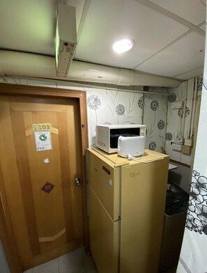 Cocina compacta con refrigerador, microondas y una puerta con el símbolo de número.