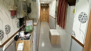 A narrow hallway with a wooden desk, a security camera, and patterned wallpaper. - New Guangzhou Guesthouse - Hostel (Kowloon)