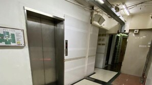 A clean, tiled hallway with an elevator and a tiled floor leading to another room. - New Guangzhou Guesthouse - Hostel (Kowloon)