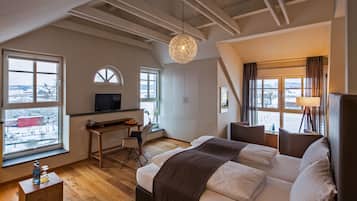 Una camera da letto con un letto, una scrivania, una televisione e ampie finestre.