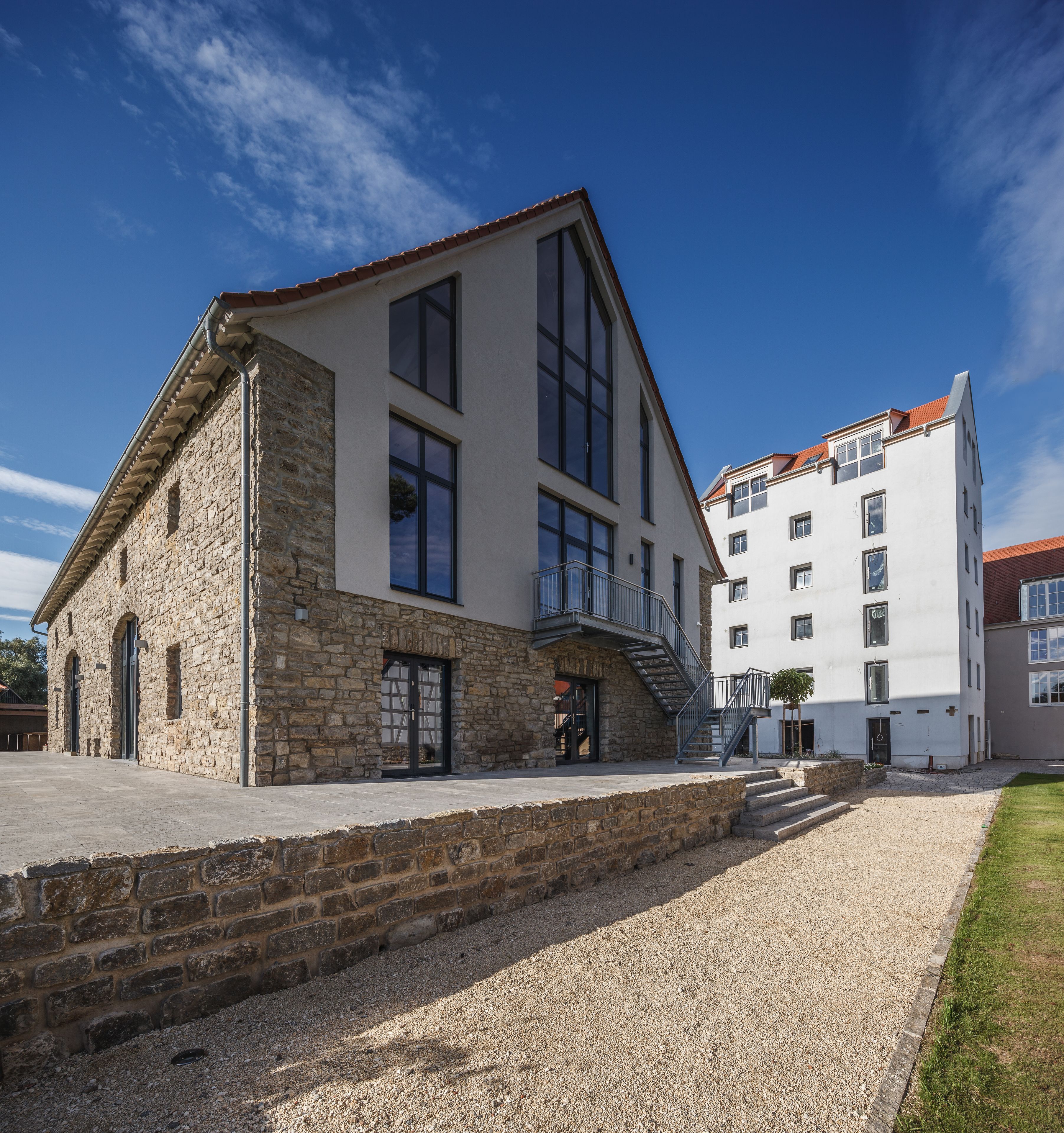 A building with a stone facade and a modern extension with large windows and a balcony.