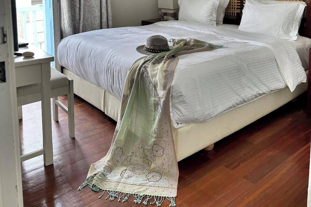 Quarto com cama, escrivaninha, cadeira, luminária pendente e janela com cortinas.