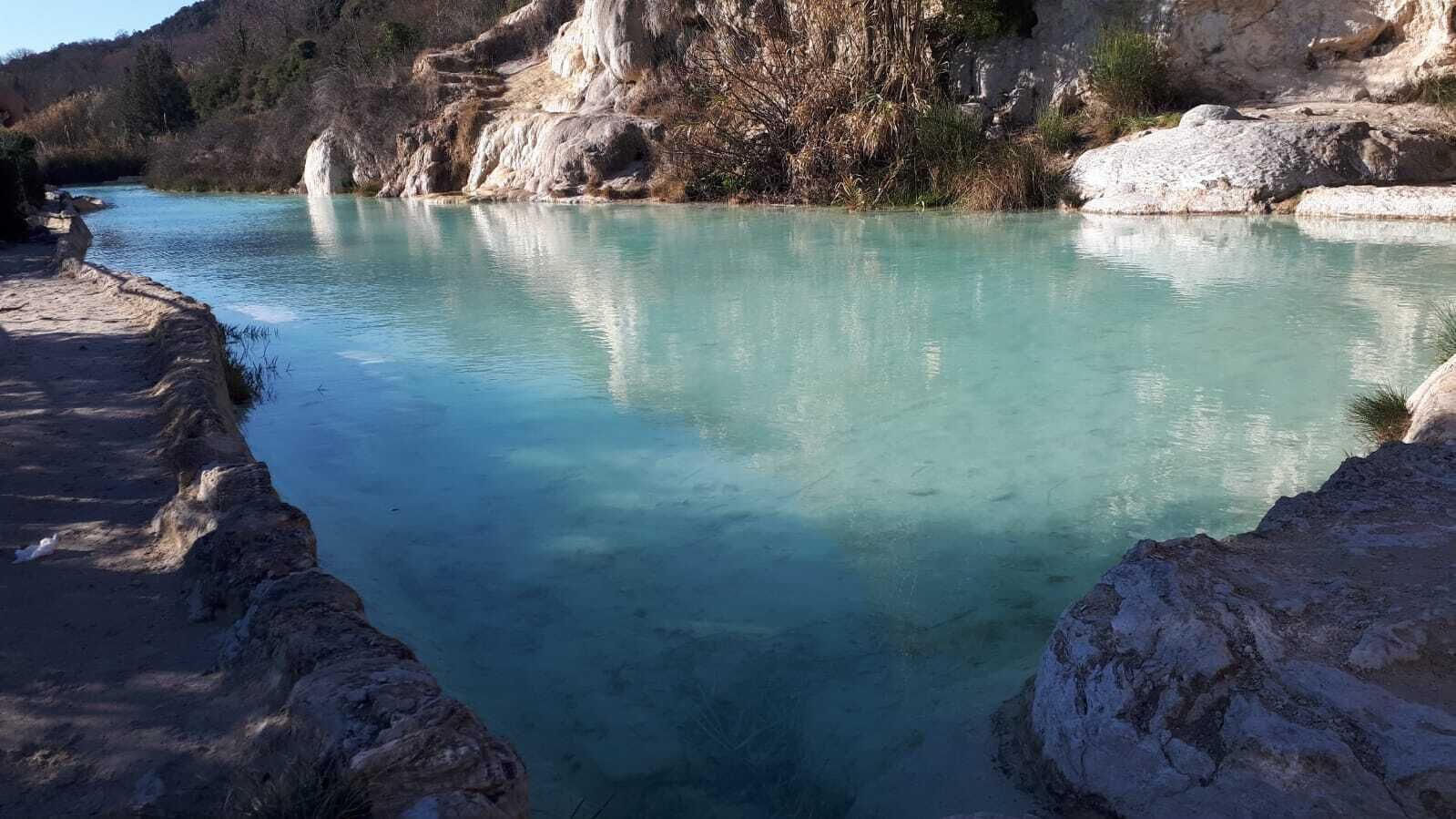 A clear turquoise river with rocky banks and a mountainous backdrop.