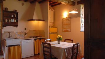 A kitchen with a dining table, chairs, a stove, and a sink.
