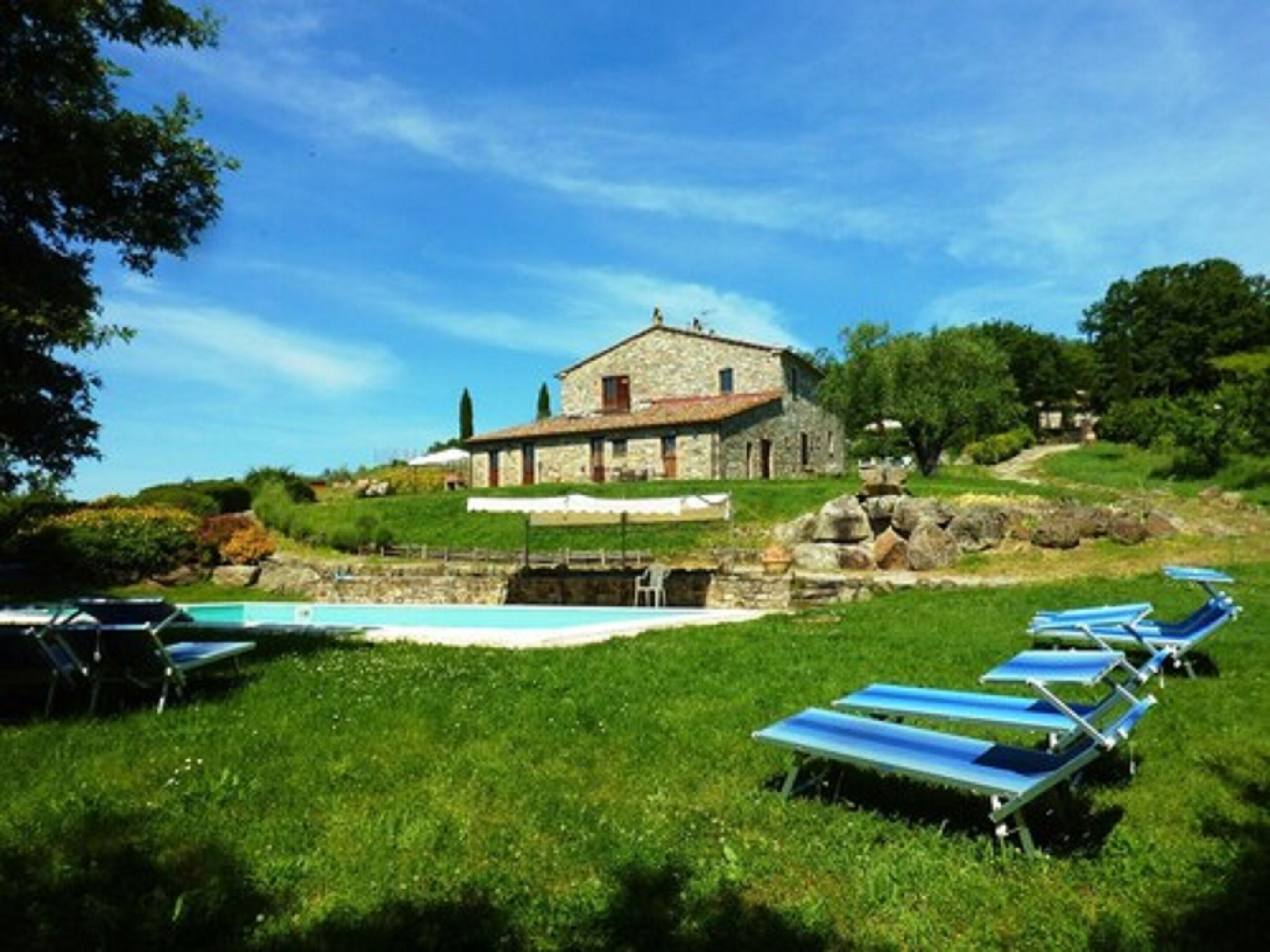 Ein Gebäude aus Stein mit Pool und Liegestühlen auf einer Rasenfläche.