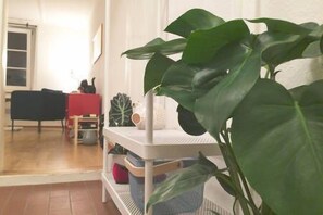 Ein Zimmer mit einem weißen Regal, einem roten Sessel und einer großen Zimmerpflanze.