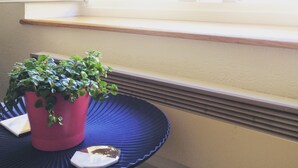 A window with a view of a building, a potted plant on a blue tray, and a white object on the tray.
