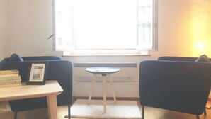 A room with two dark-colored chairs, a small round table, and a window with blinds.