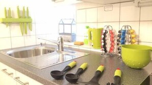 A kitchen with a sink, green utensil holder, and various kitchen tools on the counter.