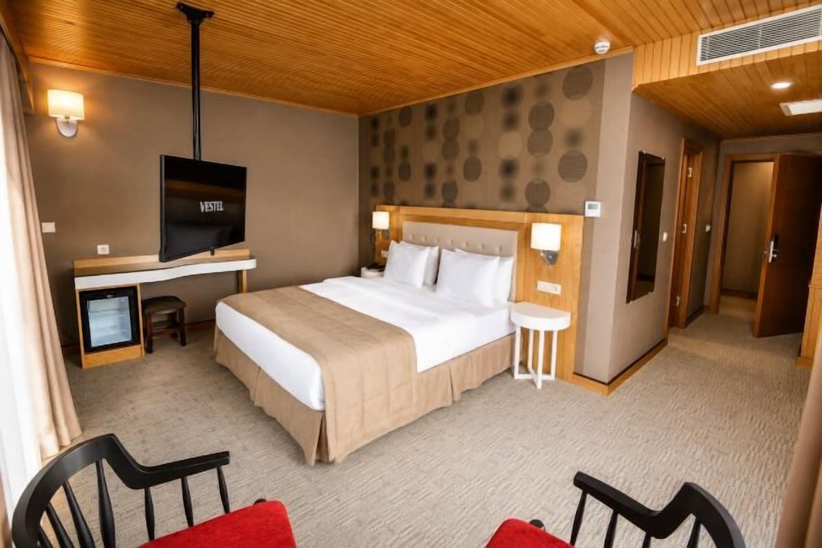 Ein Hotelzimmer mit Bett, Schreibtisch mit Fernseher, Stuhl und kleinem Tisch.