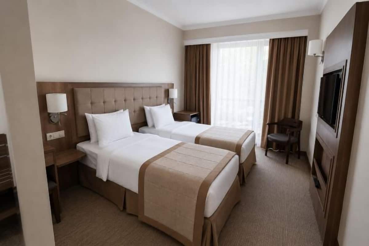 A hotel room with two beds, a TV, a desk, and a chair.