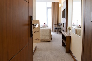 Une chambre d’hôtel avec un lit, une chaise, un bureau, une télévision et un miroir.