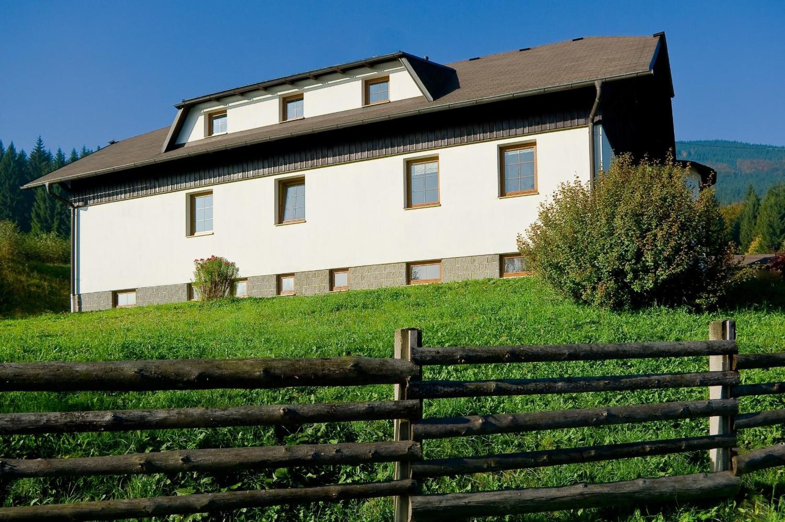 A two-story building with a sloped roof, multiple windows, and a stone foundation.