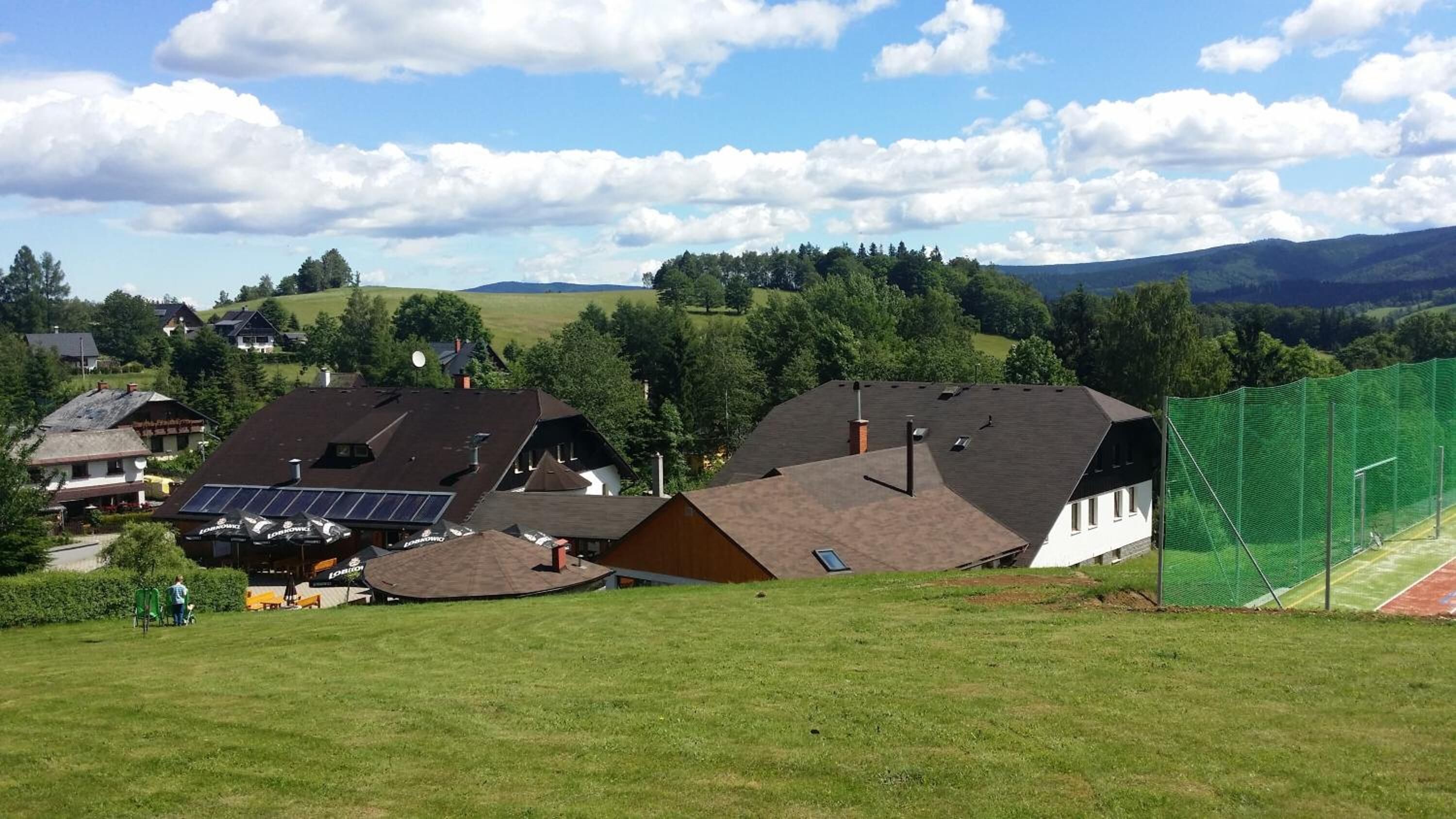 Un quartier résidentiel avec des maisons, un terrain de sport verdoyant et une montagne en arrière-plan.