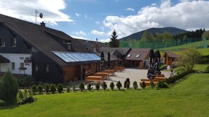 A lodge with a large dining area, outdoor seating, and a mountain backdrop. - Penzion Pepovka (Bela pod Pradedem)