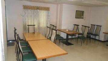 A dining area with a long wooden table and multiple chairs.