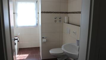 Une salle de bain avec des toilettes, un lavabo et une fenêtre.