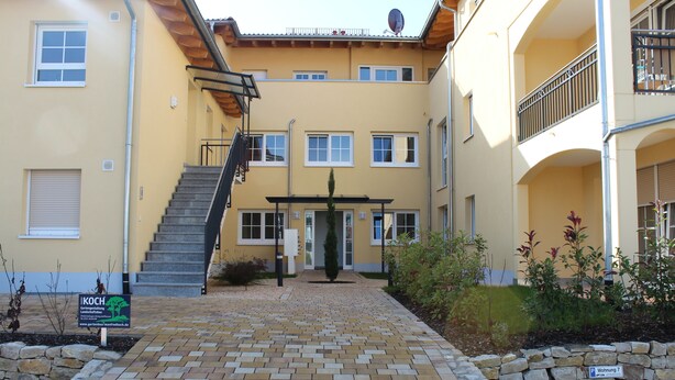 A multi-story building with a central entrance, a staircase, and a paved walkway leading to the entrance. - Appartement Vanii (Rust)