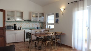 A compact kitchen with a dining area, featuring cabinets, a microwave, a stove, and a dining table with chairs. - Appartement Vanii (Rust)