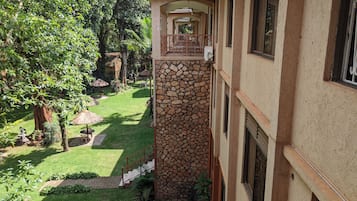 A building with a stone staircase leading to a covered outdoor area, surrounded by greenery and a well-maintained lawn.