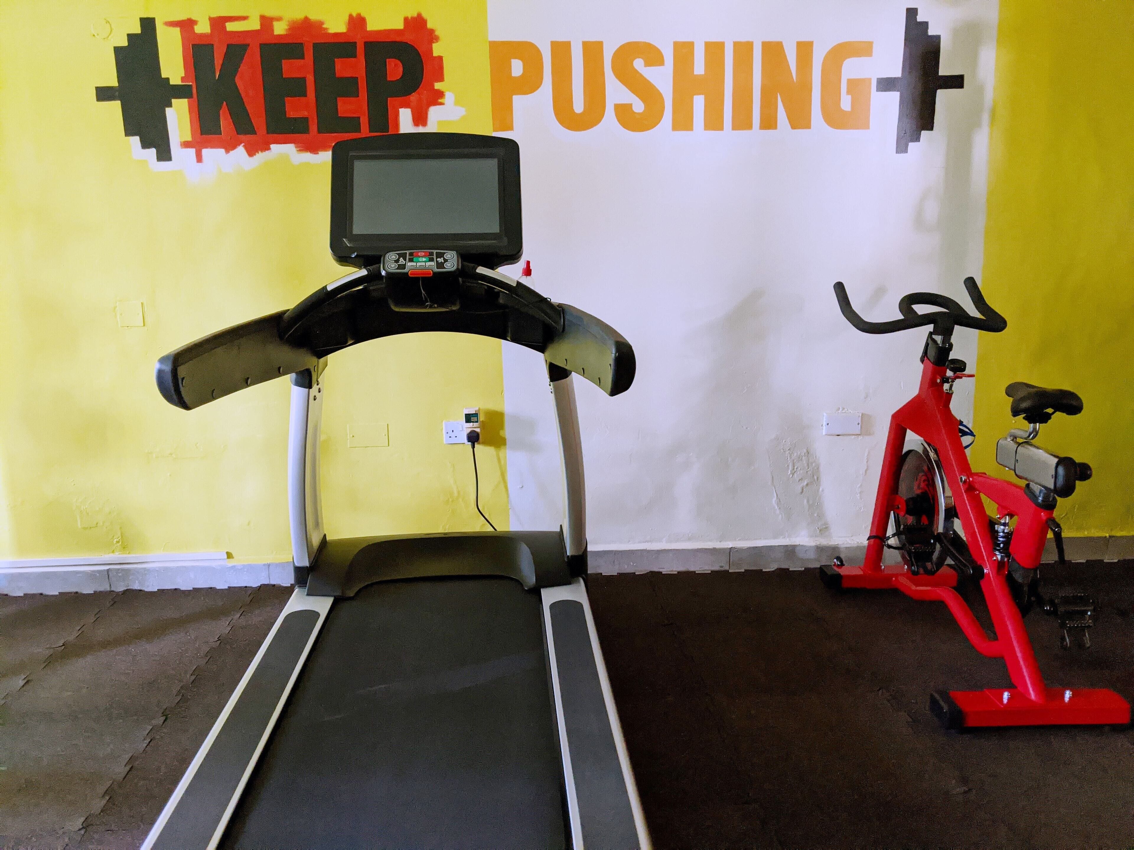 A gym with a treadmill and a stationary bike.
