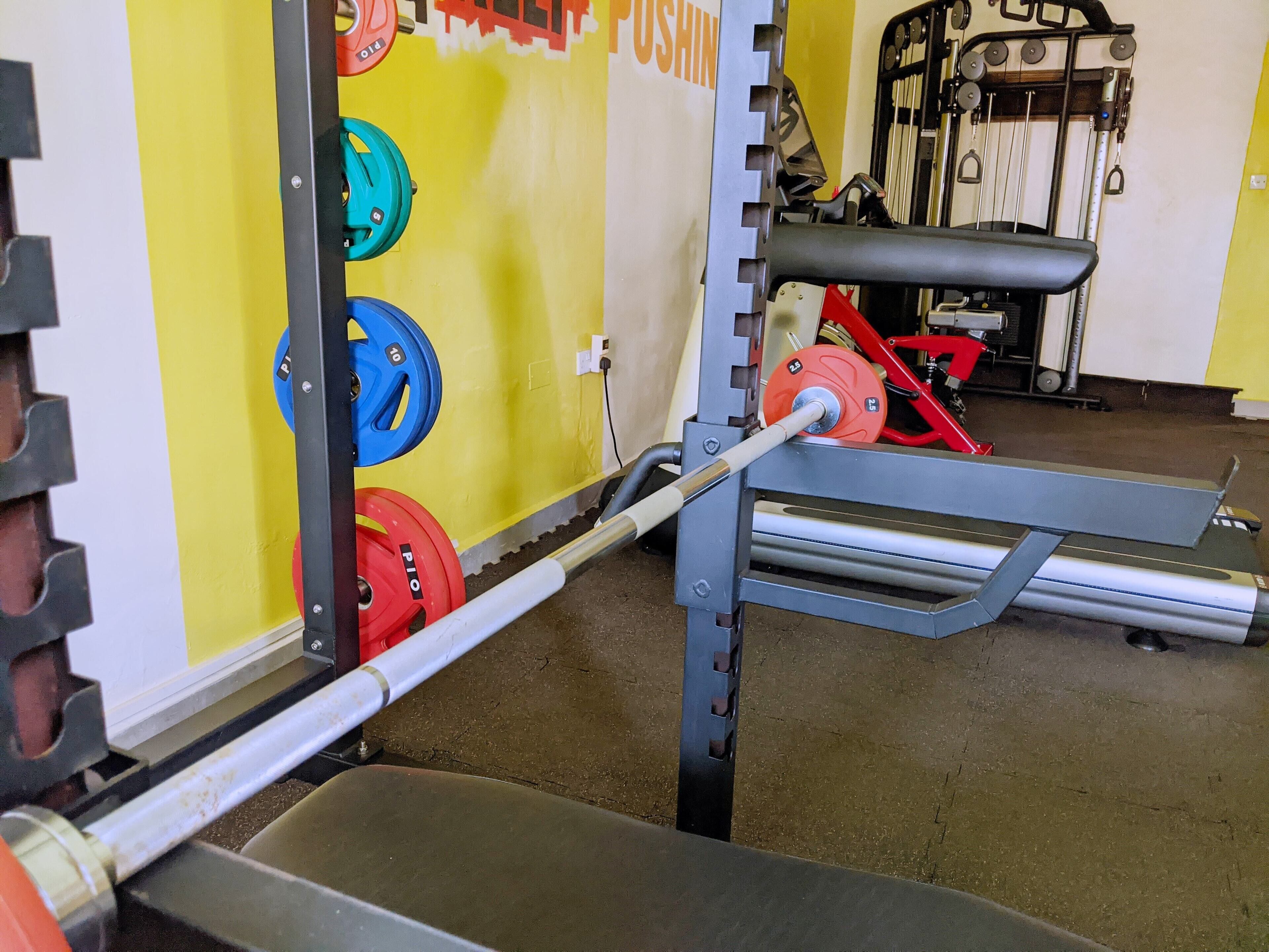 A weightlifting area with a bench press, a squat rack, and various weight plates.
