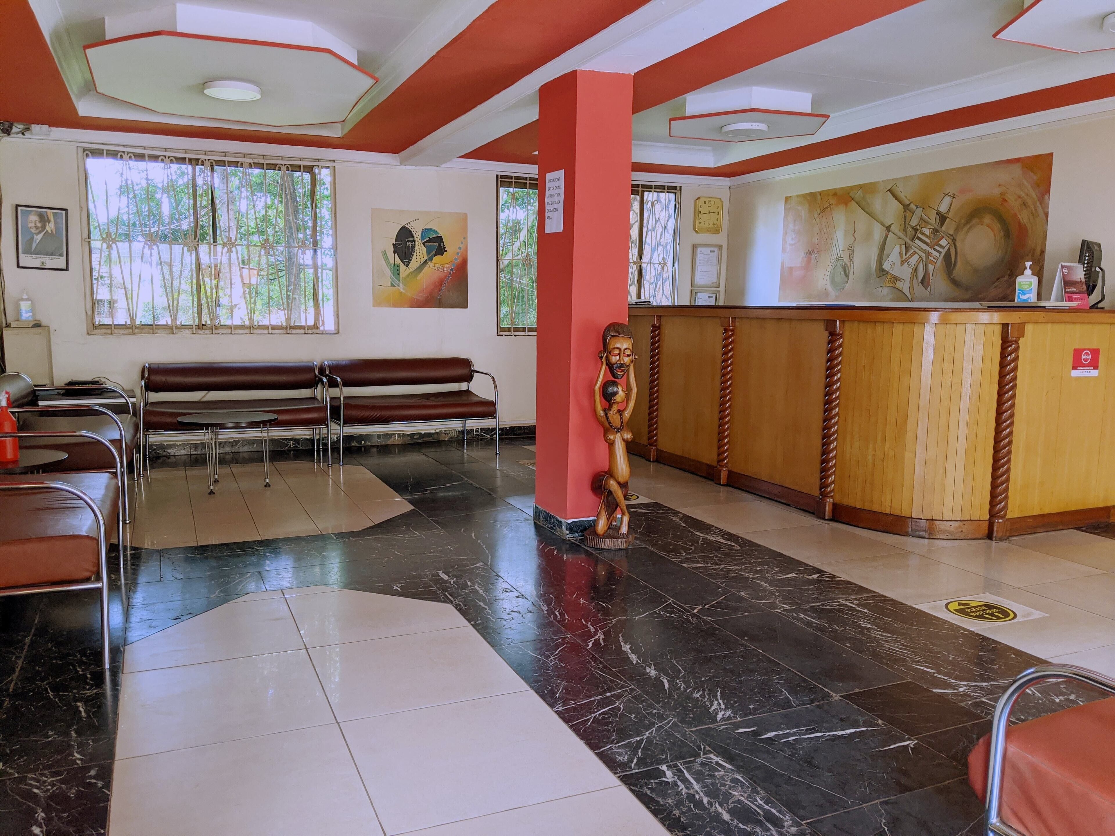 A reception area with a wooden counter, a sculpture, and a bench.