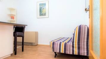Una habitación con cama, una silla, un escritorio y un radiador.