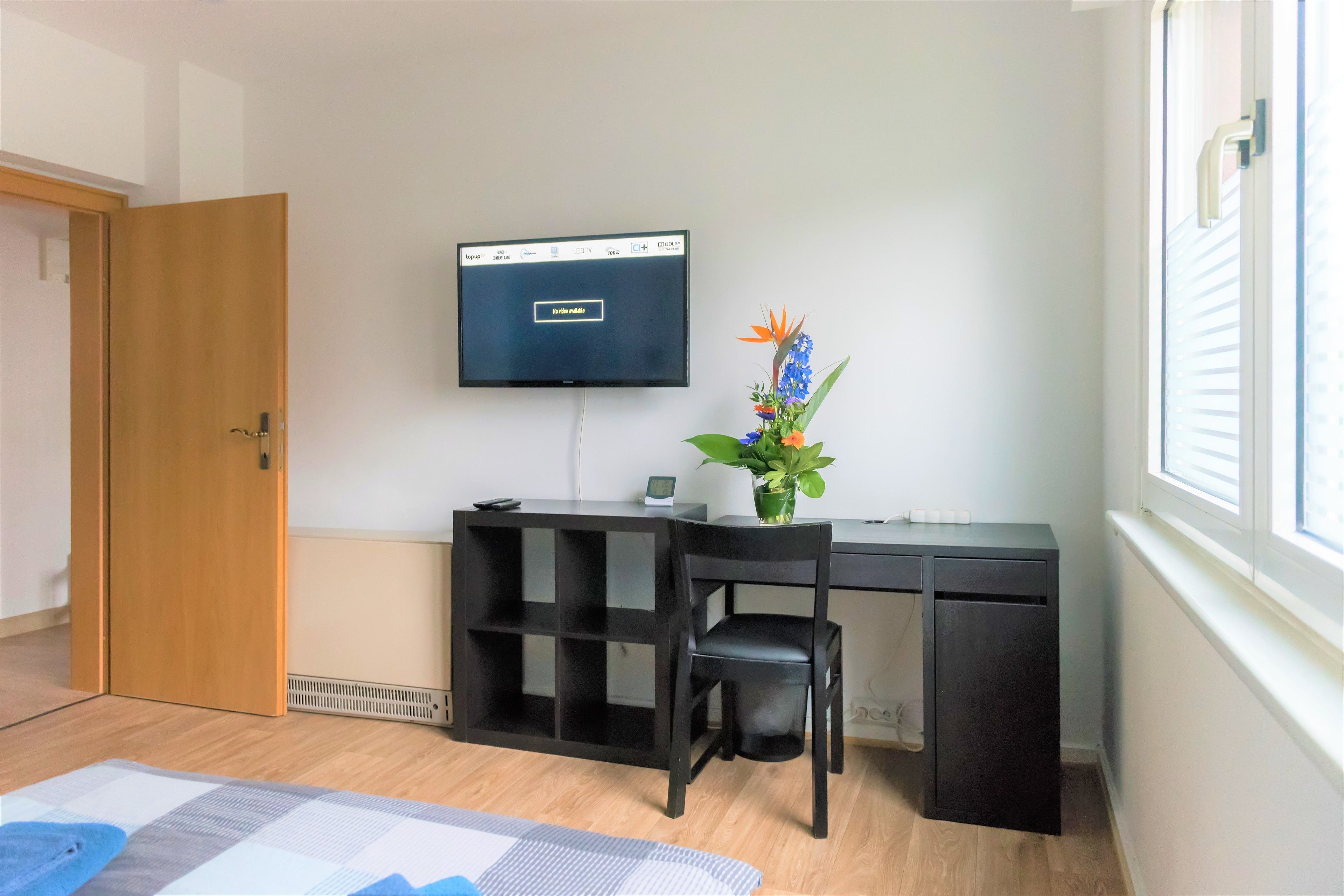 Een kamer met een bureau, stoel, televisie en een potplant.