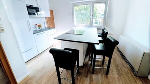A modern kitchen with white cabinets, a black countertop, and a window providing natural light. - Schaefer Apartments GmbH (Muehlheim am Main)
