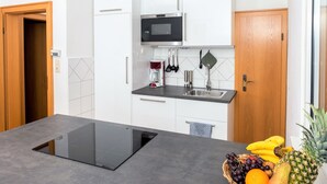 A modern kitchen with white cabinets, a black countertop, a built-in microwave, and a sink. - Schaefer Apartments GmbH (Muehlheim am Main)