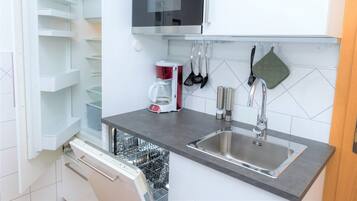 A modern kitchen with a built-in dishwasher, a stainless steel sink, and a microwave above the countertop.