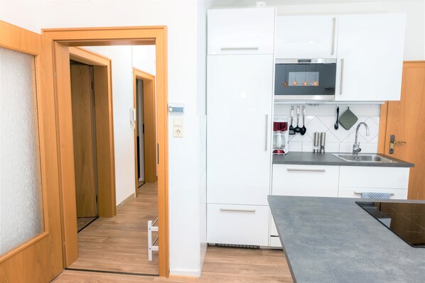 A modern kitchen with white cabinets, a built-in oven, and a stainless steel sink. - Schaefer Apartments GmbH (Muehlheim am Main)