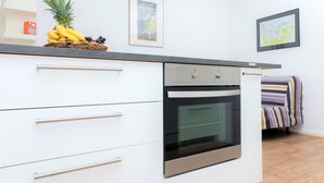 A modern kitchen with white cabinetry, a stainless steel oven, and a fruit basket on the countertop. - Schaefer Apartments GmbH (Muehlheim am Main)