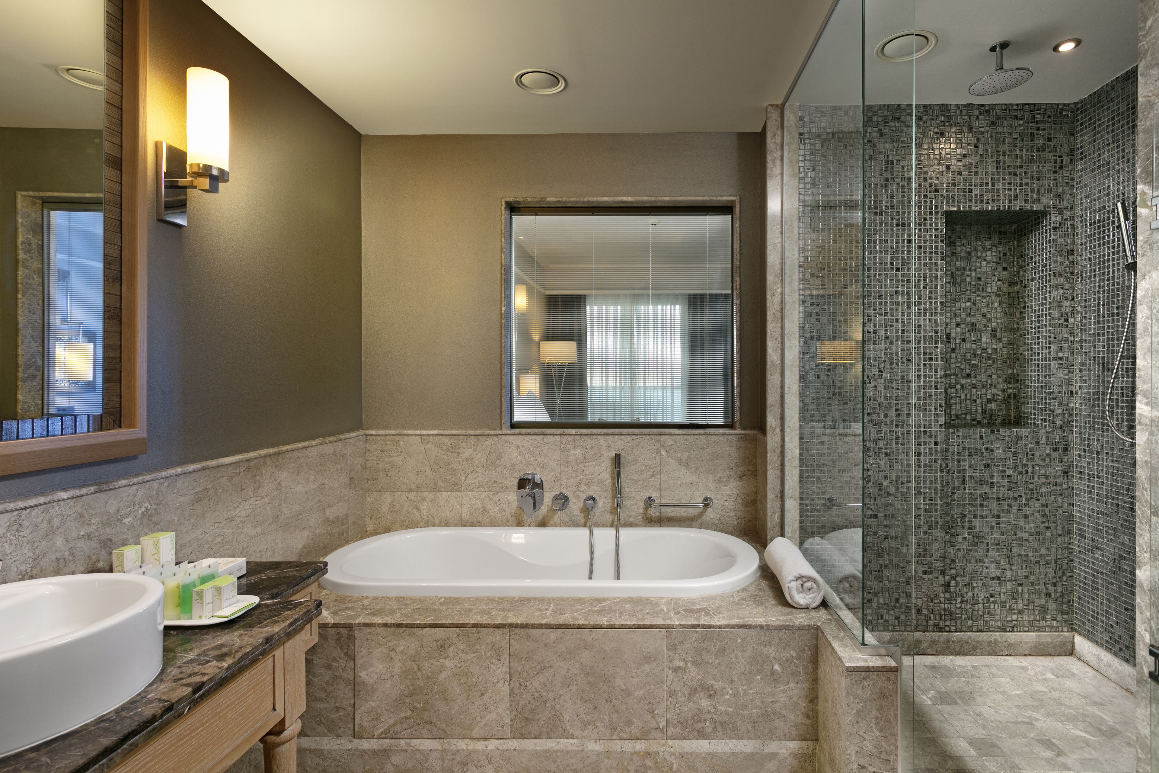 A modern bathroom with a large bathtub, a glass-enclosed shower, and a vanity with a mirror and countertop.