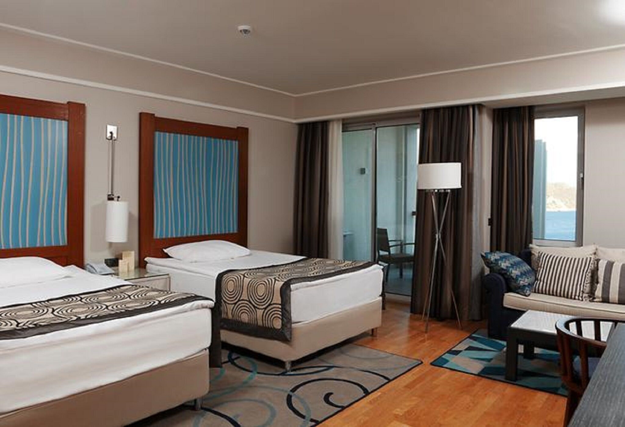 Une chambre d’hôtel avec deux lits, un canapé, un bureau et une vue sur l’extérieur.