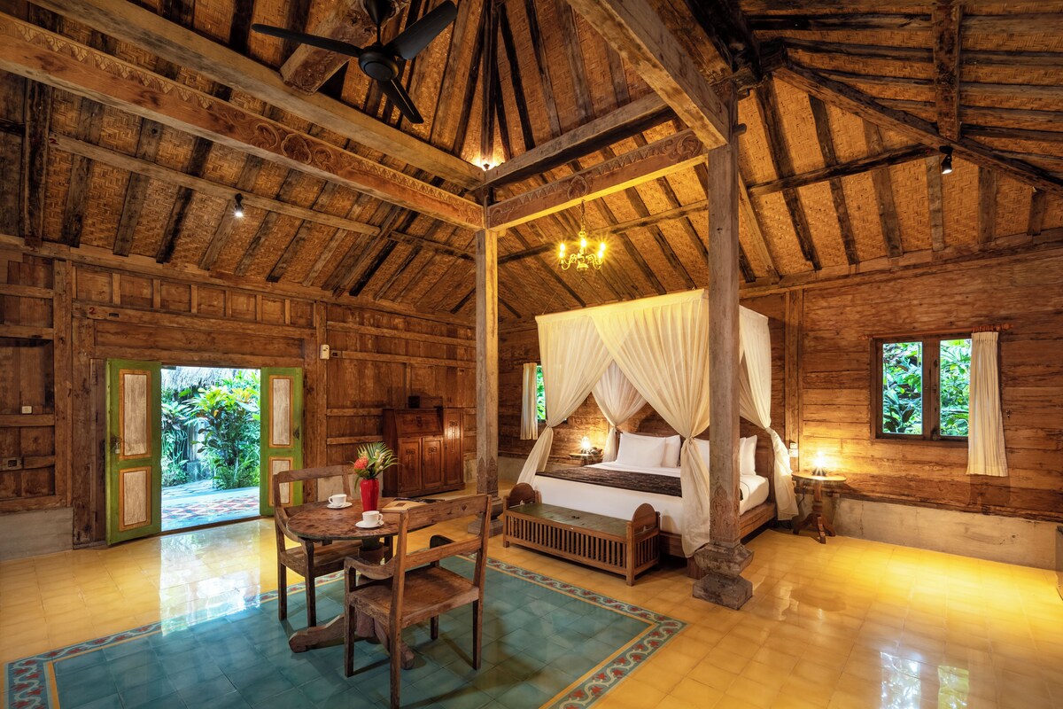 A wooden room with a bed, a table, chairs, and a ceiling fan.