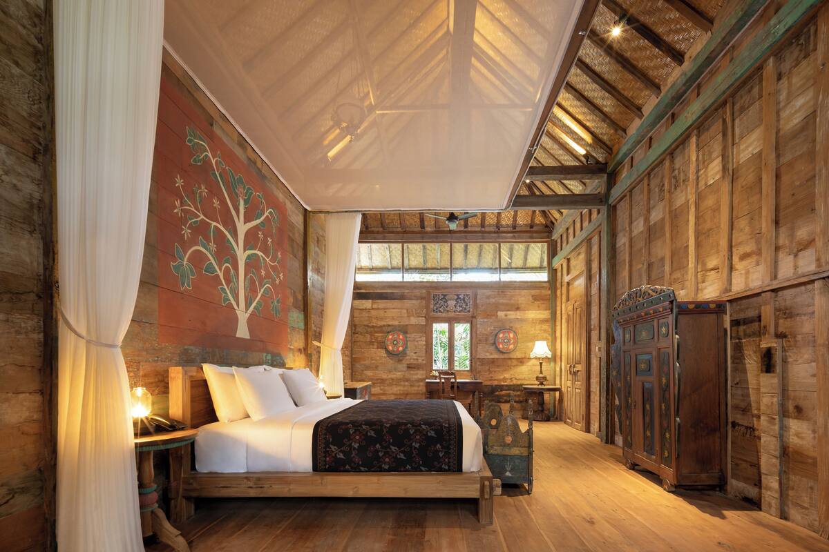 A wooden room with a bed, a table, and a cabinet.