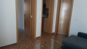 Ein Zimmer mit Holzboden, einem Glastisch und einem grauen Sofa.
