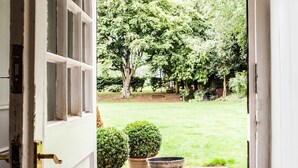 A doorway leading to a garden with potted plants and a lawn.