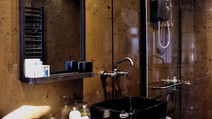 Un baño con un espejo grande, un lavabo negro y una ducha.