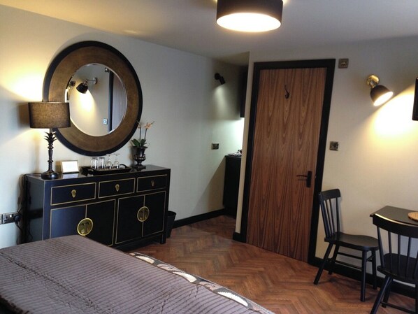 A bedroom with a bed, dresser, mirror, and a door leading to another room. - Gower View Luxury bed & Breakfast (Tenby)