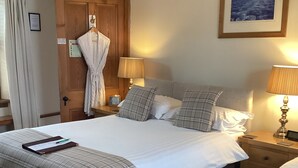 Habitación de hotel con una cama grande, dos mesitas de noche, una puerta de madera y un cuadro enmarcado en la pared.