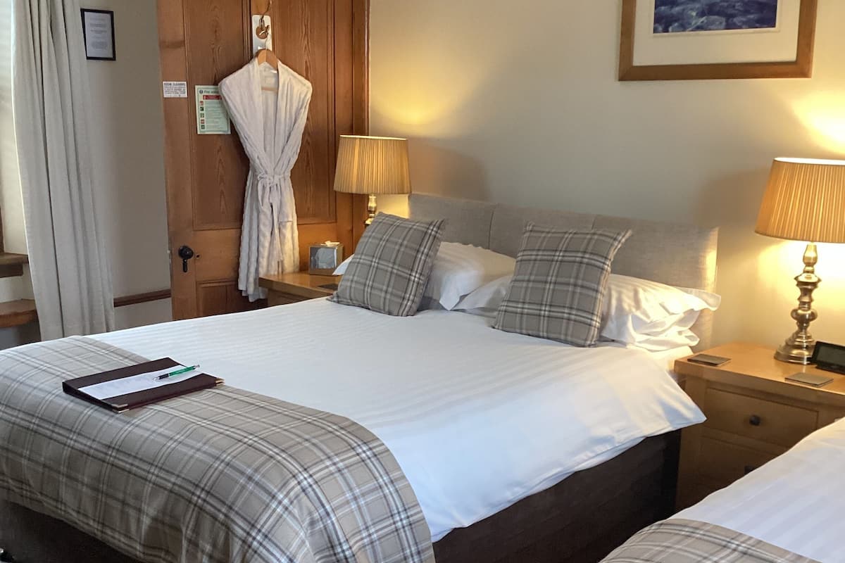A hotel room with a large bed, two bedside tables, a wooden door, and a framed picture on the wall.