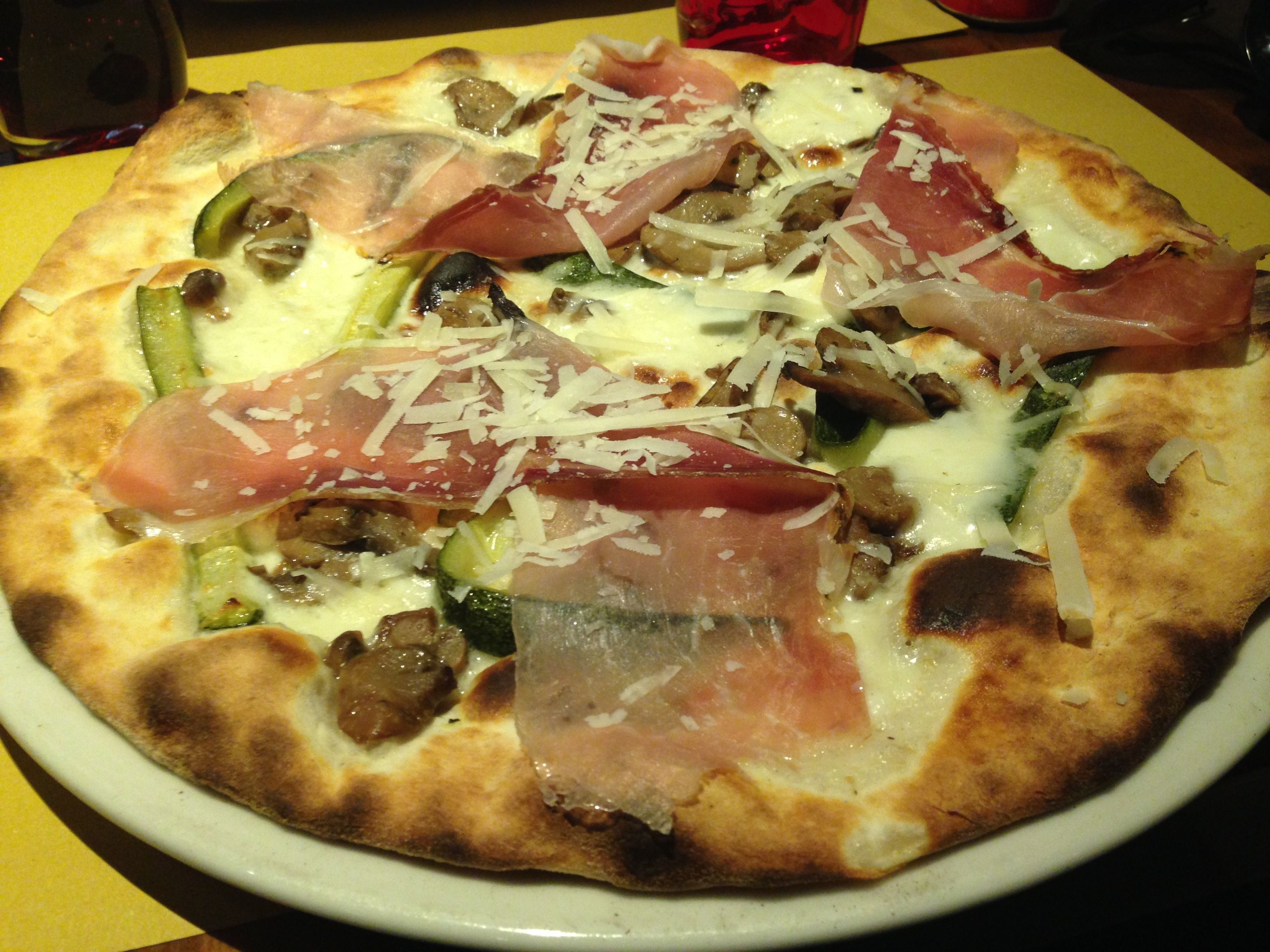 Eine Pizza mit verschiedenen Belägen auf einem weißen Teller.