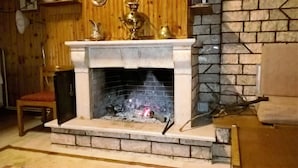 Una chimenea con revestimiento de piedra, una repisa adornada con objetos decorativos y una pared de madera al fondo.